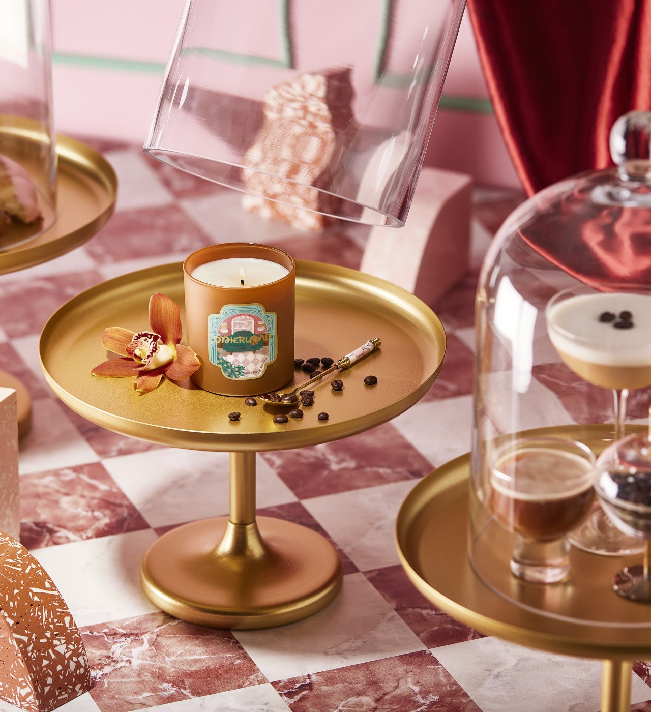 Candle on a gold tray with decorative elements on a checkered tablecloth